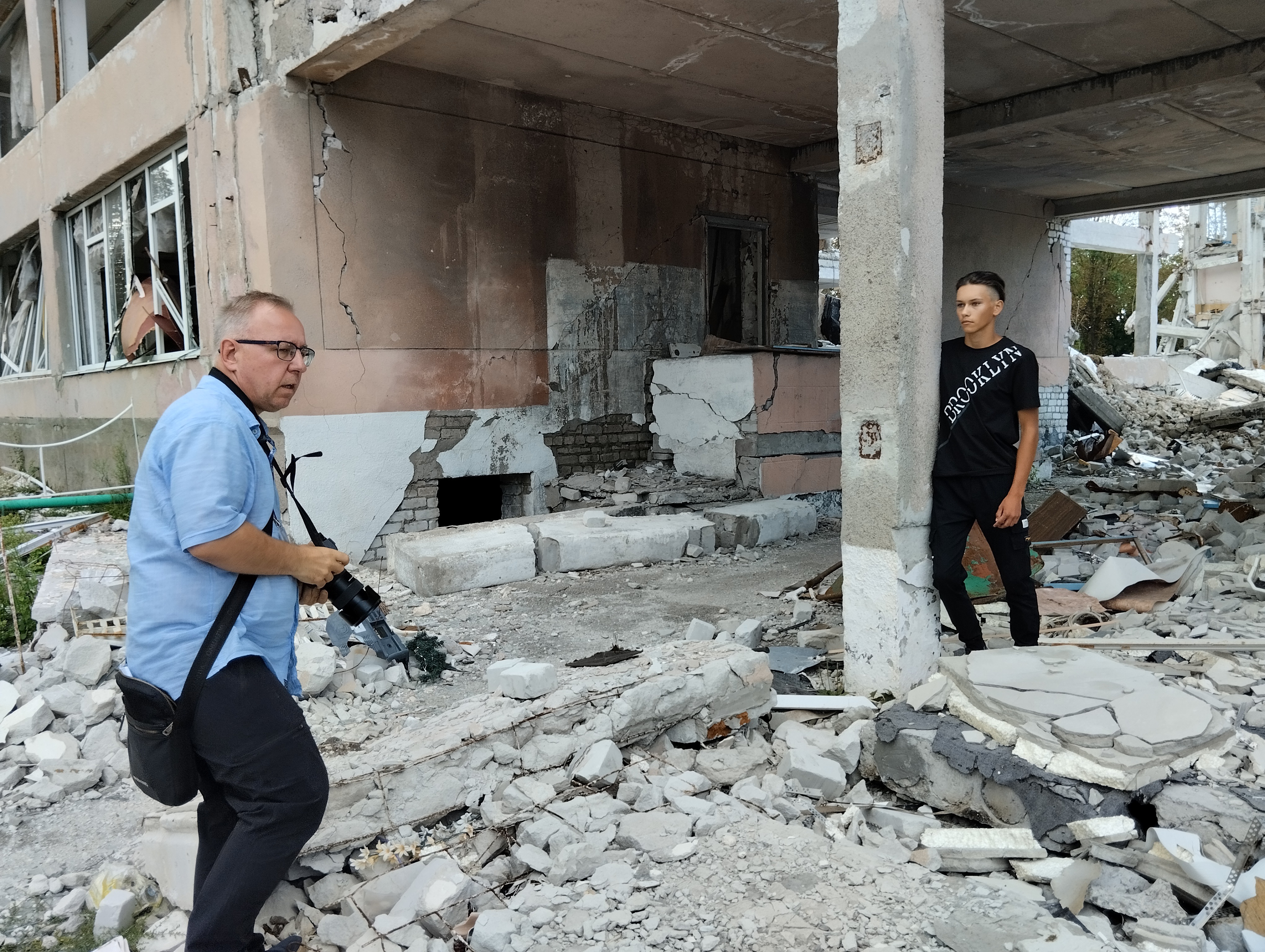 Адам Касперкевич фотографує зруйнований ліцей у місті Лозова. Фото автора